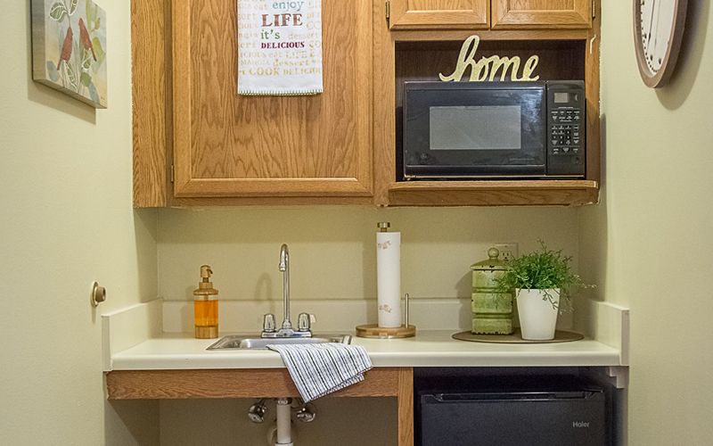 A cozy kitchen with wooden cabinets, a sink, and a microwave on the counter.