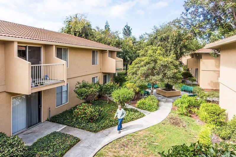 A scenic apartment complex with lush gardens and a winding walkway.