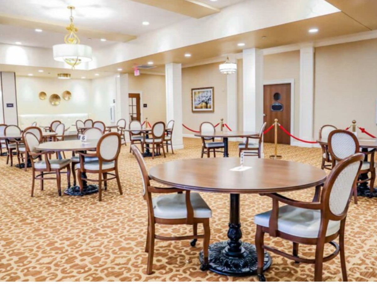 An elegant dining area with tables, chairs, and chandeliers.