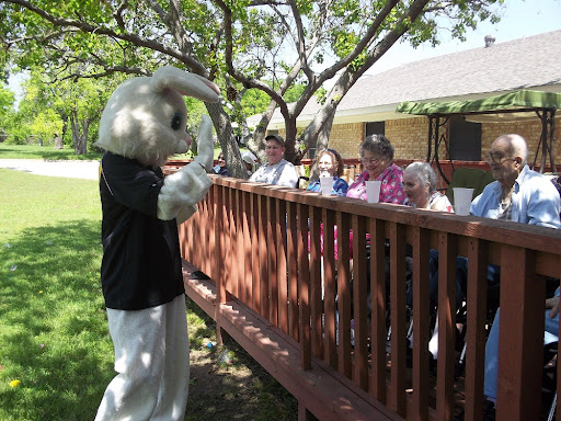 A mascot in a bunny costume engaging with an audience outdoors.