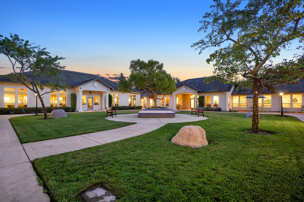 A spacious single-story home with a well-maintained lawn and pathway, set against an evening sky.