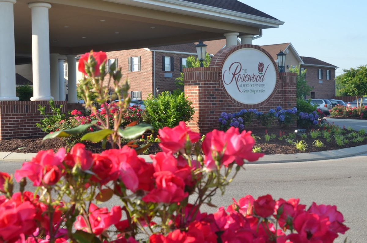 A vibrant garden in front of a building with a welcoming sign.