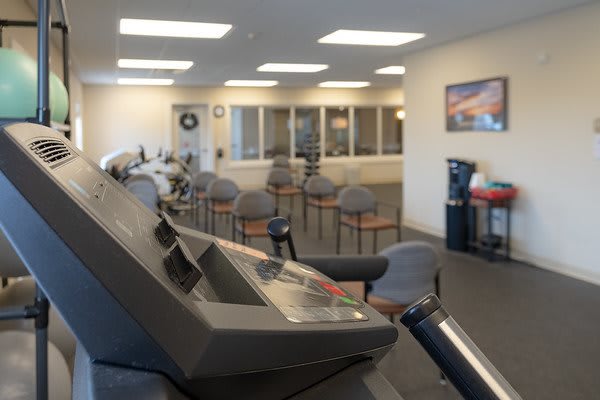 A gym with exercise equipment and a waiting area with chairs.