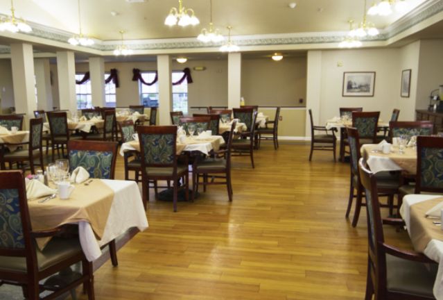 An empty dining room with neatly arranged tables and wooden flooring.
