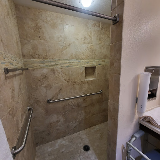 A spacious, modern shower area featuring tiled walls and accessibility bars.