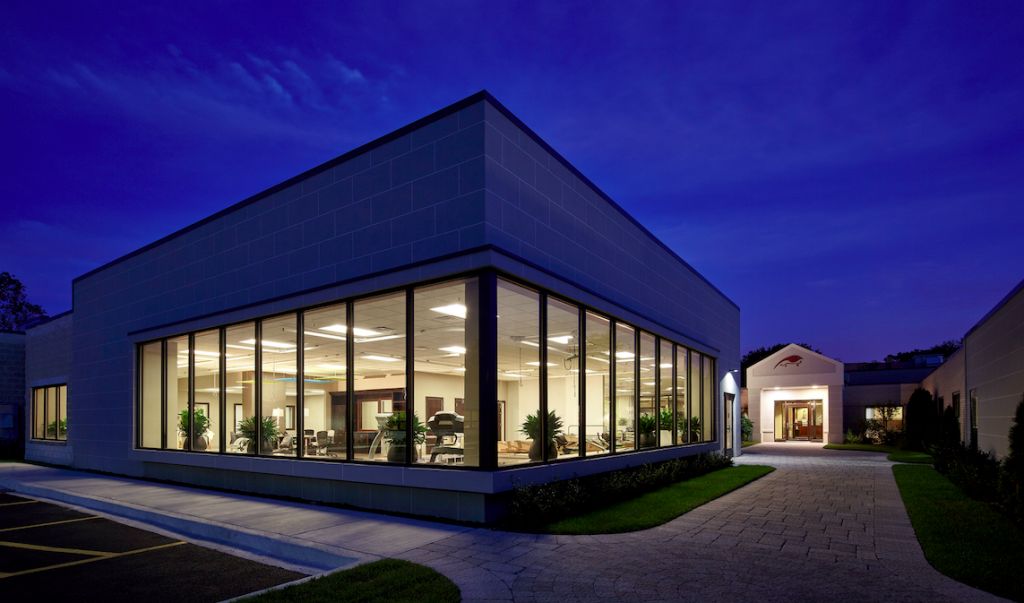 A modern glass-fronted building is illuminated at night, showcasing its sleek architectural design.