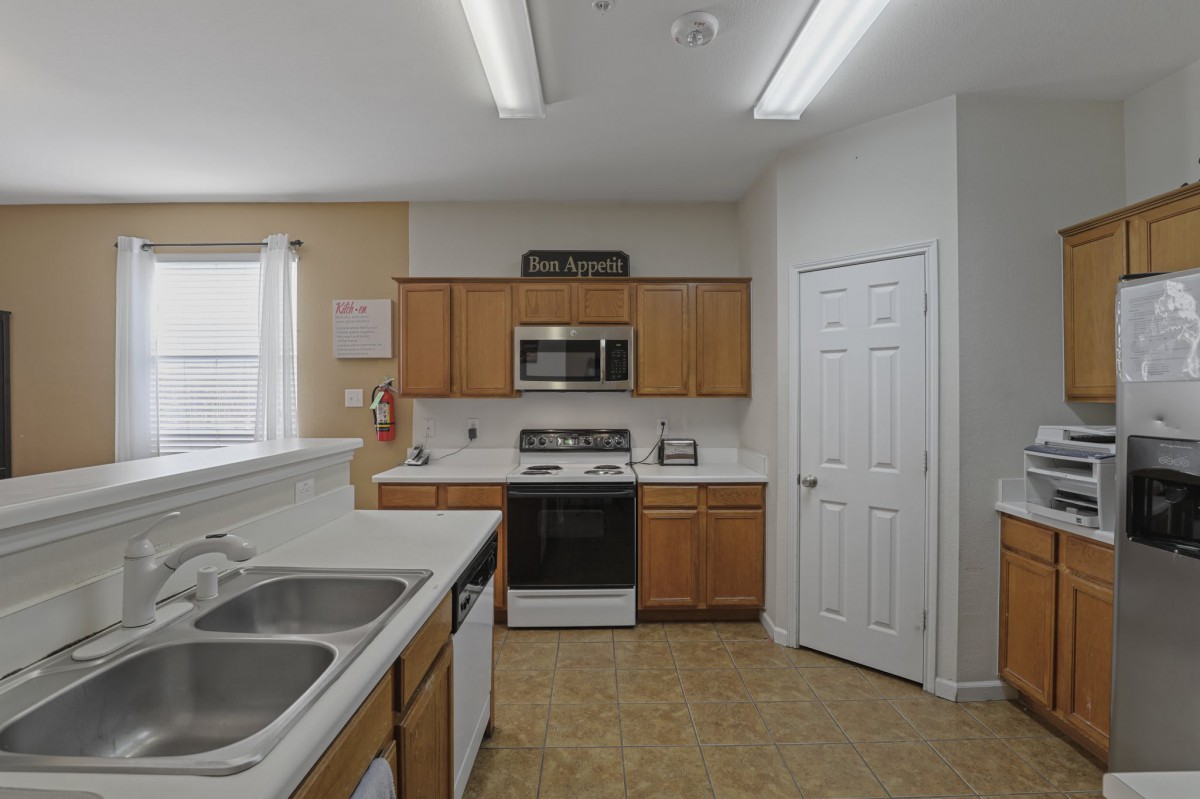 Modern kitchen featuring wooden cabinets, a microwave, an oven, and a dual sink.