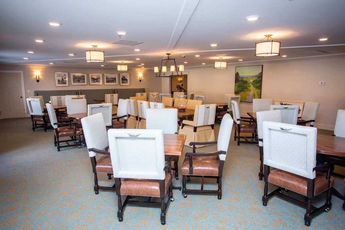 An elegantly arranged dining room with tables and chairs, well-lit and decorated with artwork on the walls.
