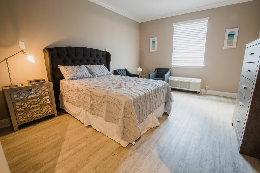 A cozy bedroom with a neatly made bed, chairs, and a window.
