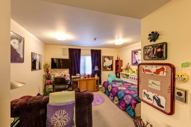 A cozy, colorful bedroom with a variety of decor, including artwork on the walls and patterned bedding.