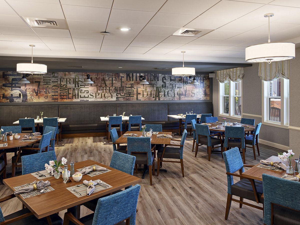 A modern dining area with blue upholstered chairs and wooden tables, featuring stylish lighting and decor.