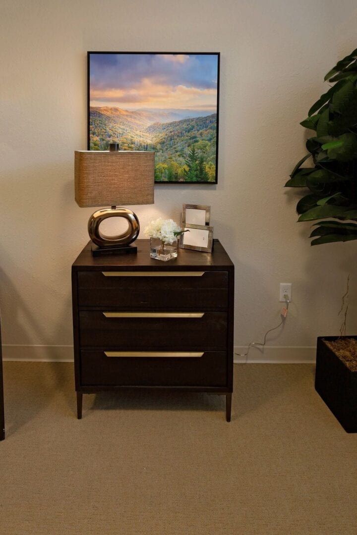A stylish nightstand with a modern lamp and artwork above, creating a cozy interior design setup.