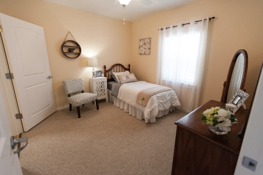 A cozy, traditionally styled bedroom with a single bed and warm decor.