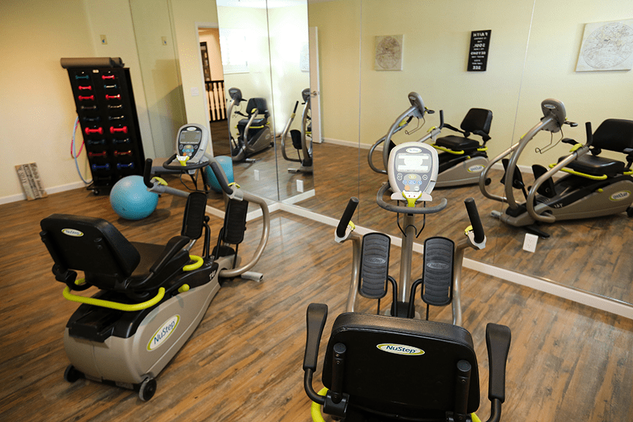 A modern gym equipped with stationary bikes and an exercise ball, featuring mirrored walls.