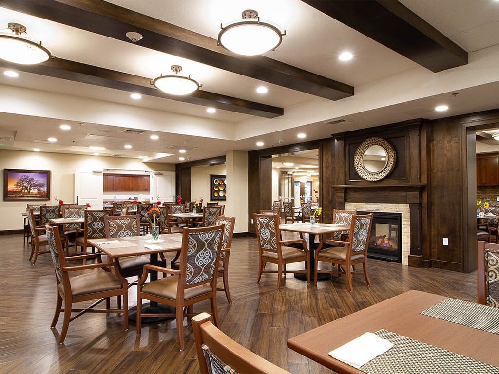 A modern dining room with neatly arranged tables and chairs, featuring elegant lighting and a cozy atmosphere.