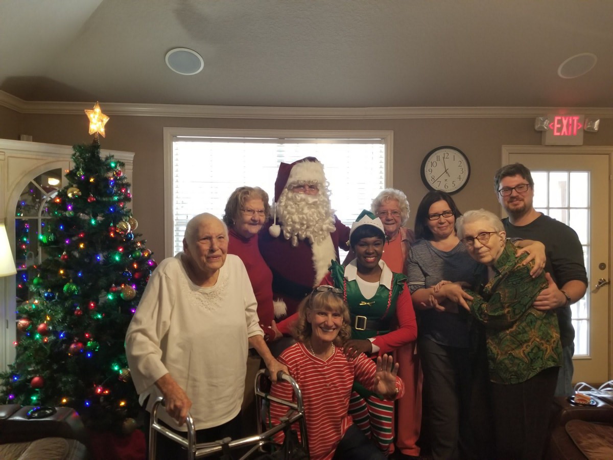 A festive group photo featuring Santa Claus and a decorated Christmas tree, capturing the joyful spirit of a family gathering.