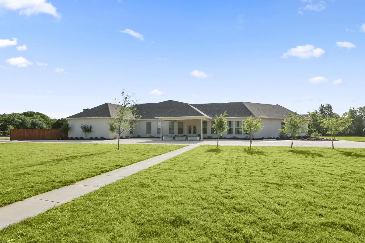 A spacious house with a well-maintained lawn under a clear blue sky.