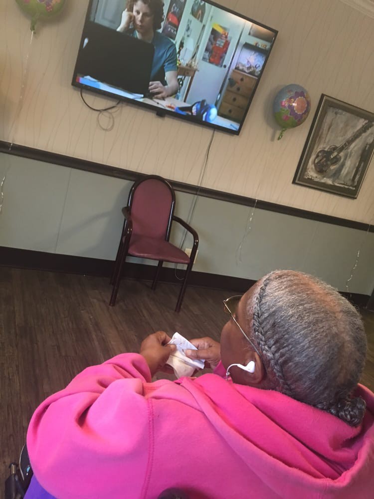 A woman sits in a chair watching television indoors.