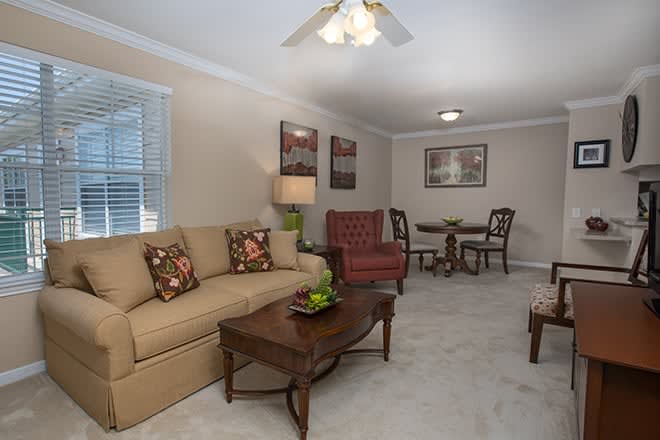 A cozy living room with a sofa, armchair, and coffee table adjacent to a small dining area.