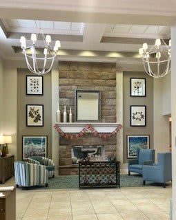 A modern and cozy living room interior with a stone fireplace, comfortable seating, and elegant chandeliers.