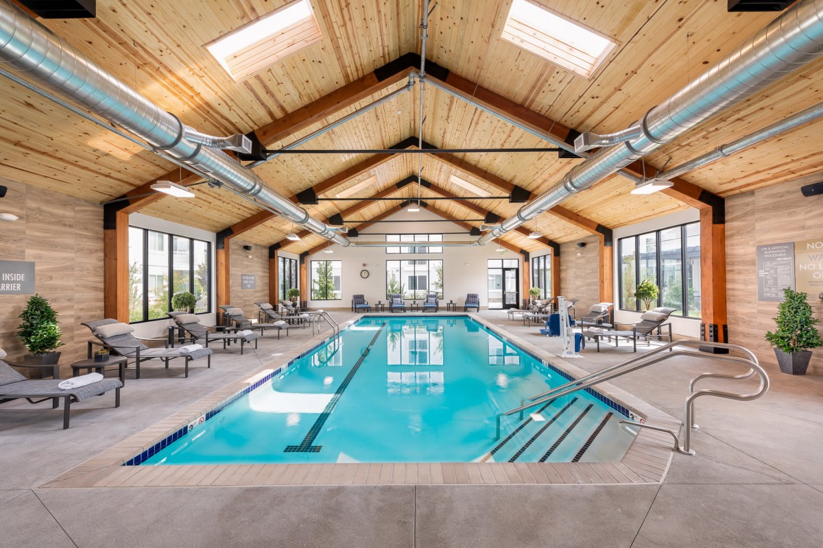 Spacious indoor swimming pool area with wooden ceiling beams and ample natural light.