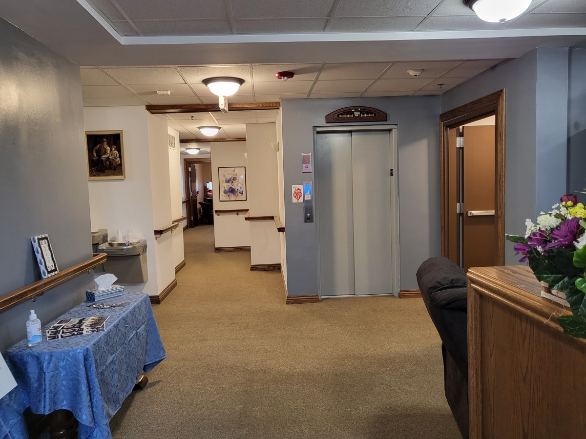 A hallway with an elevator and reception area in a building interior.