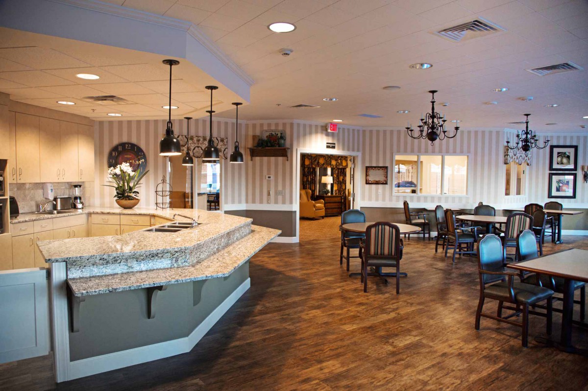 A cozy restaurant interior featuring a bar counter, dining tables, and warm lighting.