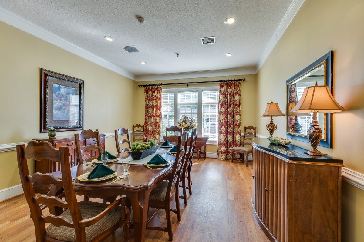 A well-decorated dining room with a wooden table, surrounded by chairs and accented by elegant curtains and decor.