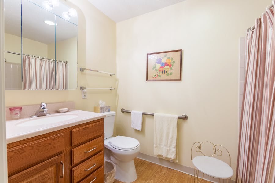 A clean and bright bathroom with a wooden cabinet, a toilet, and towels neatly arranged.