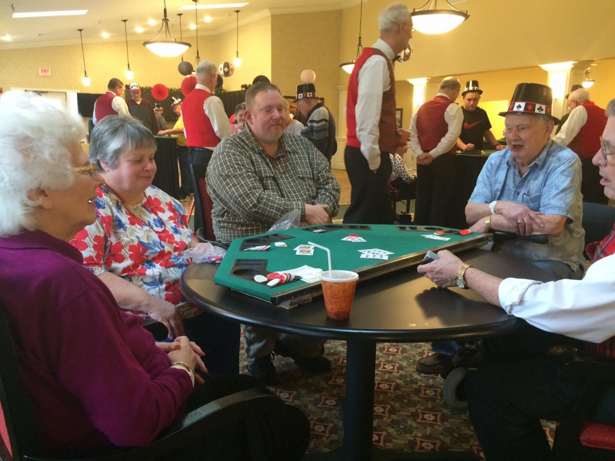 A group of people are playing poker at a table during an indoor event.