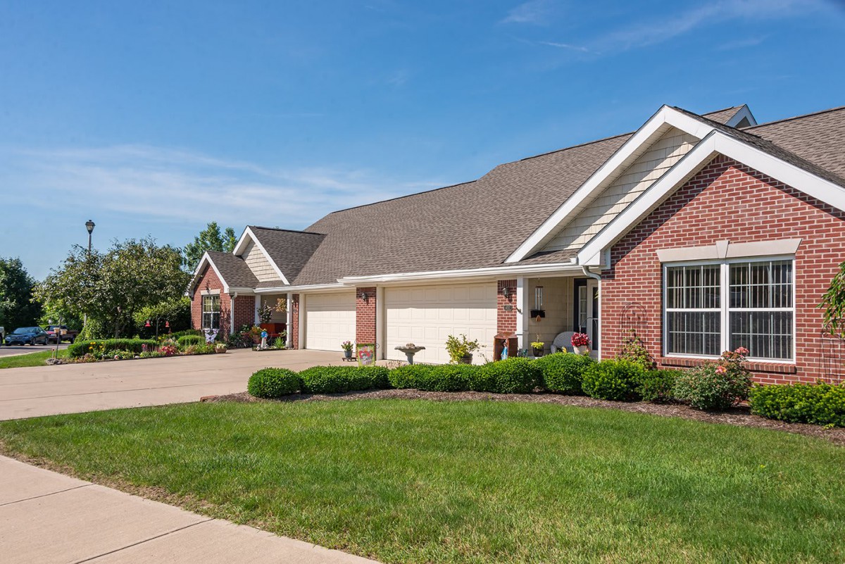 A suburban brick house with a well-maintained lawn and driveway.