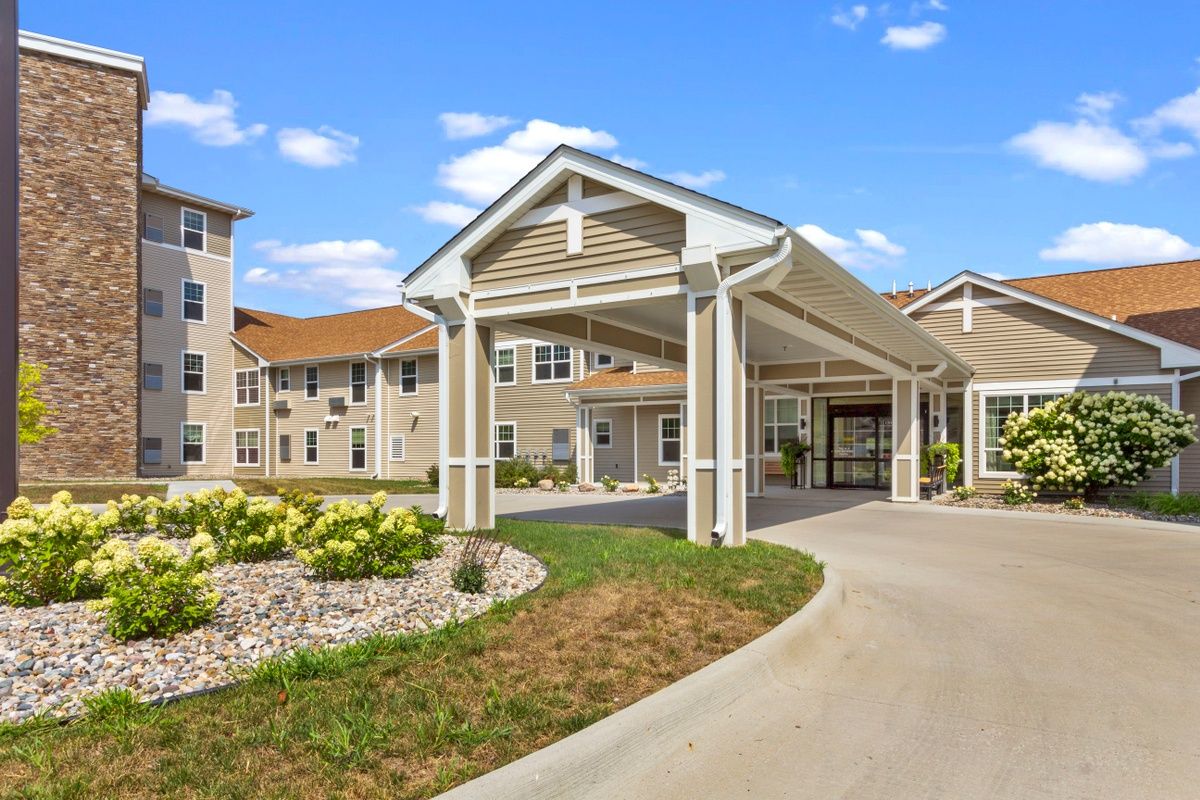 A modern residential building with a covered entrance and landscaped surroundings.