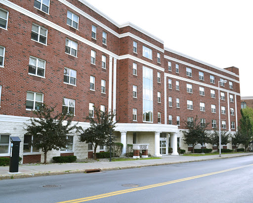 A modern brick residential building with multiple windows and a welcoming entrance.