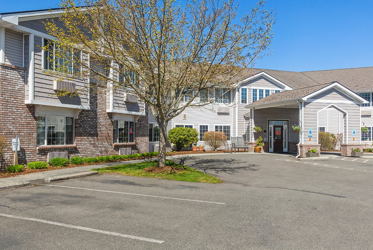 A residential building with a parking lot and landscaped surroundings.