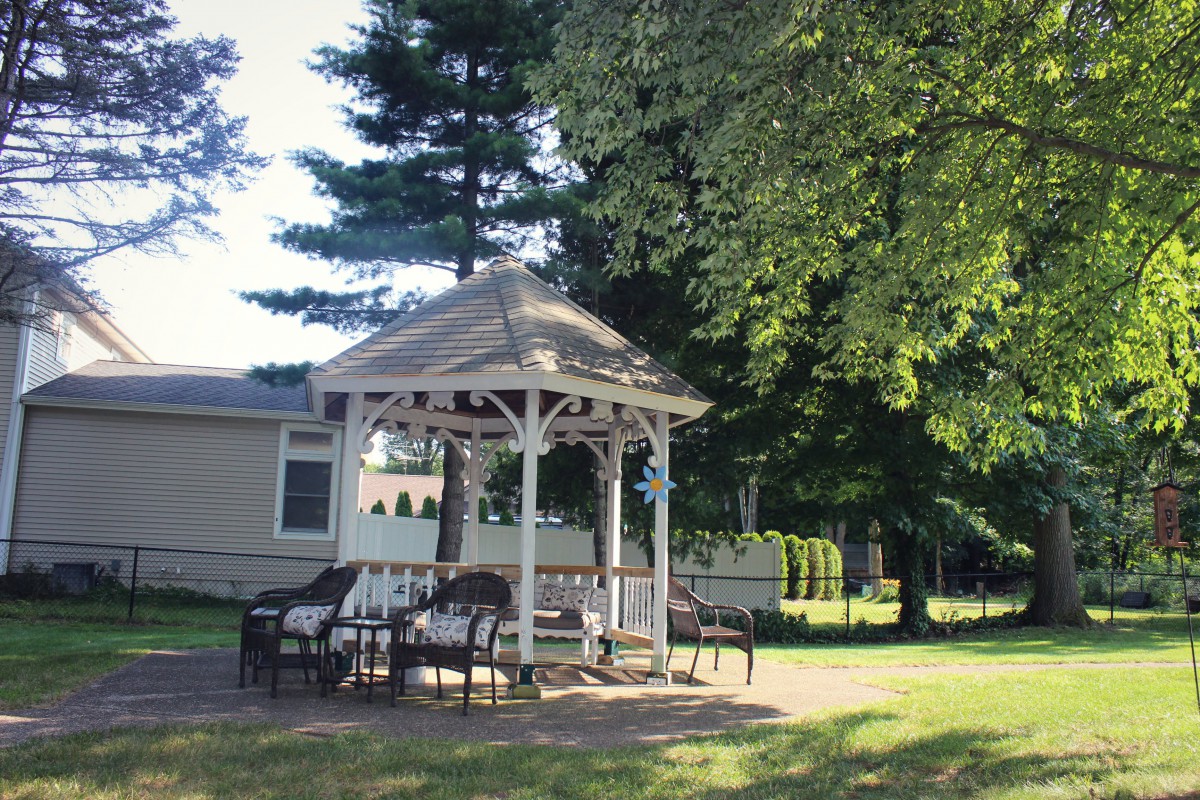 A charming gazebo surrounded by chairs in a sunlit garden.