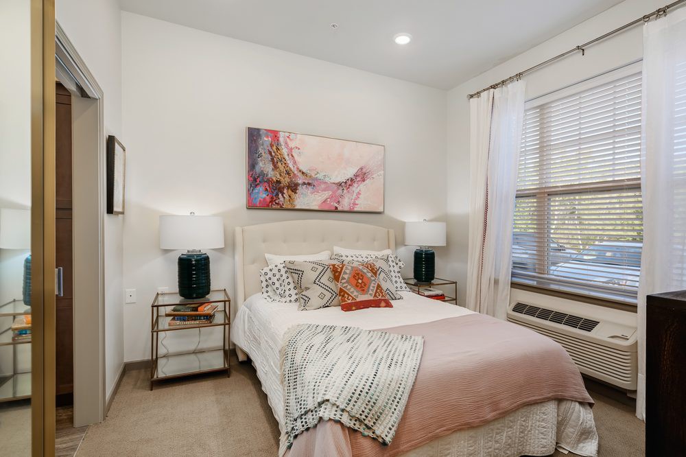 A cozy bedroom with elegant decor, featuring a bed adorned with cushions and a stylish painting above.