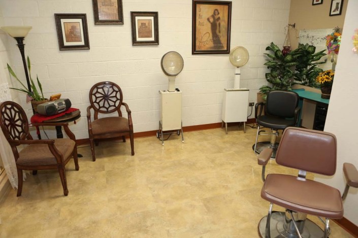 A cozy waiting area with chairs and salon equipment, adorned with wall art.