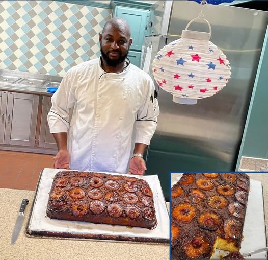 A chef proudly presents a freshly baked cake in the kitchen.