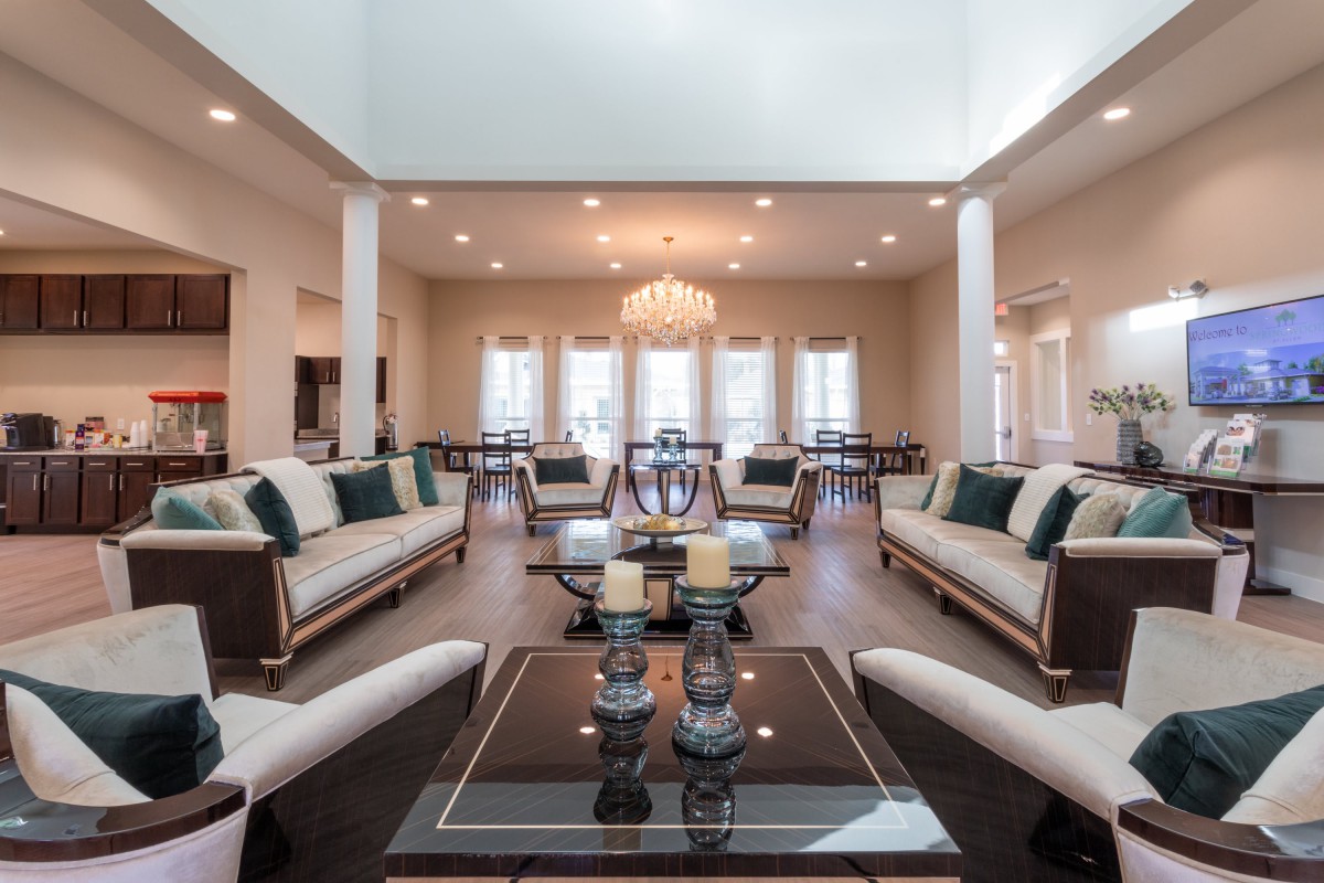 A spacious living room with elegant furniture and a chandelier, leading into a dining area.