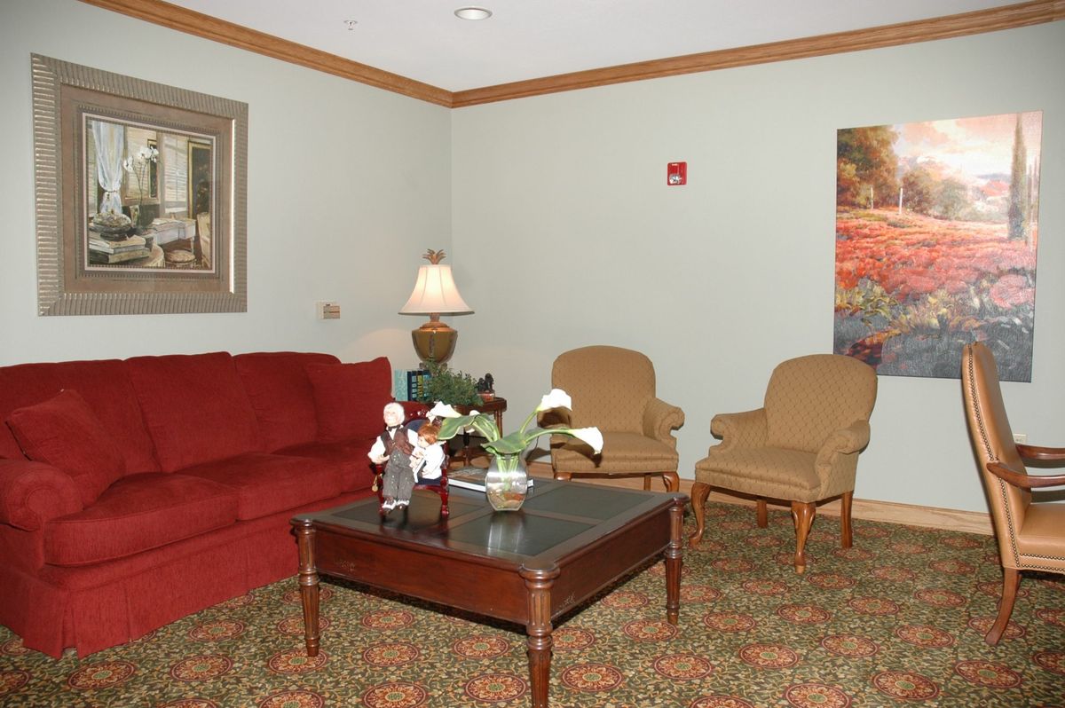A cozy living room with a red sofa, two armchairs, and a coffee table adorned with decorative items.