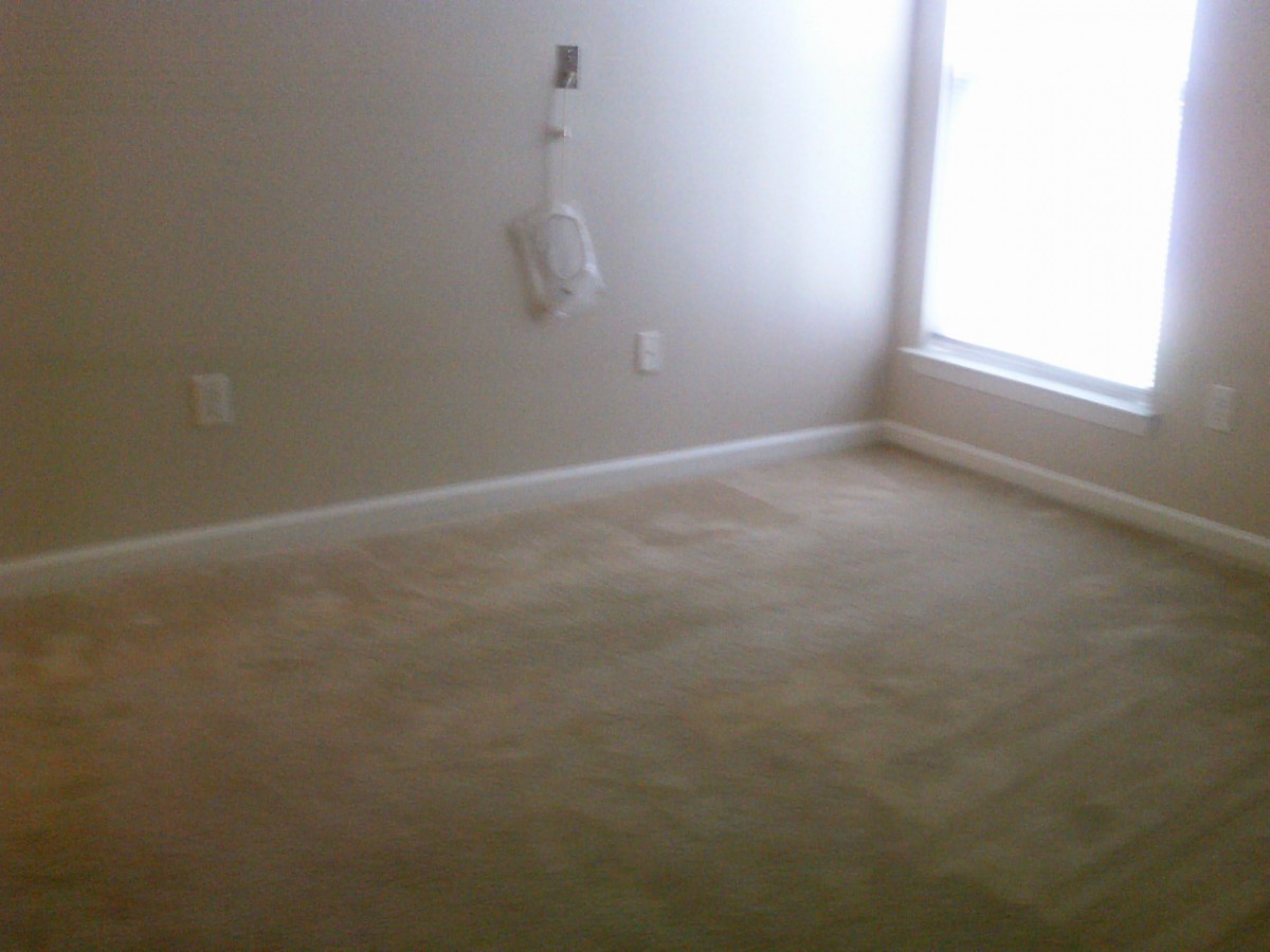 An empty room with carpet flooring and a window.