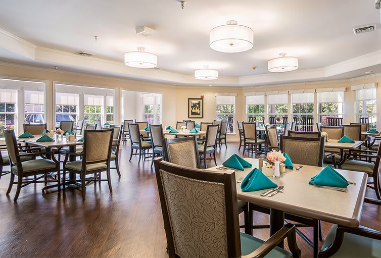 A spacious dining room with elegantly set tables and comfortable chairs.