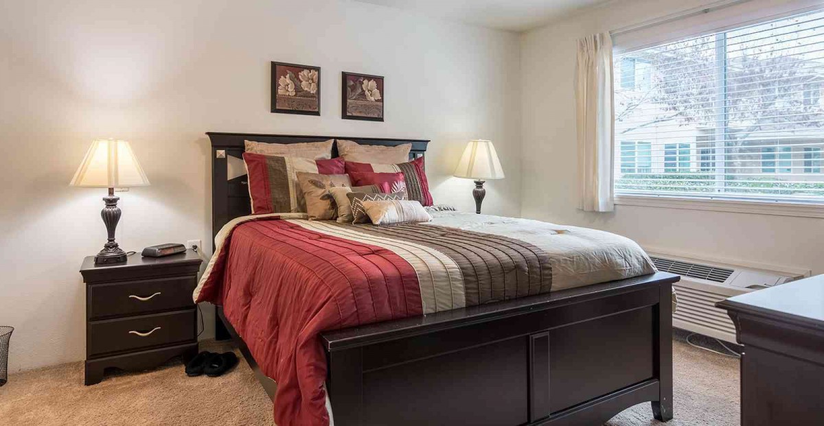 A cozy bedroom with a neatly made bed and warm decor.