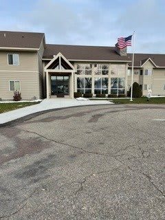 A building entrance with an American flag and surrounding pavement.