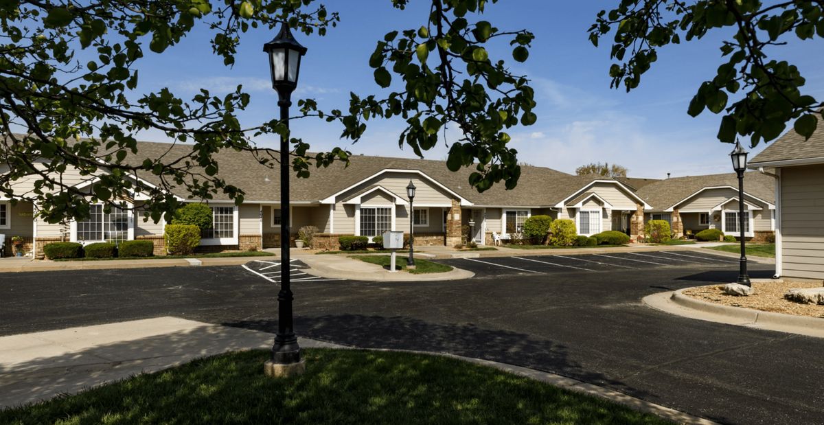 A suburban neighborhood with row houses and a streetlamp under a clear blue sky.