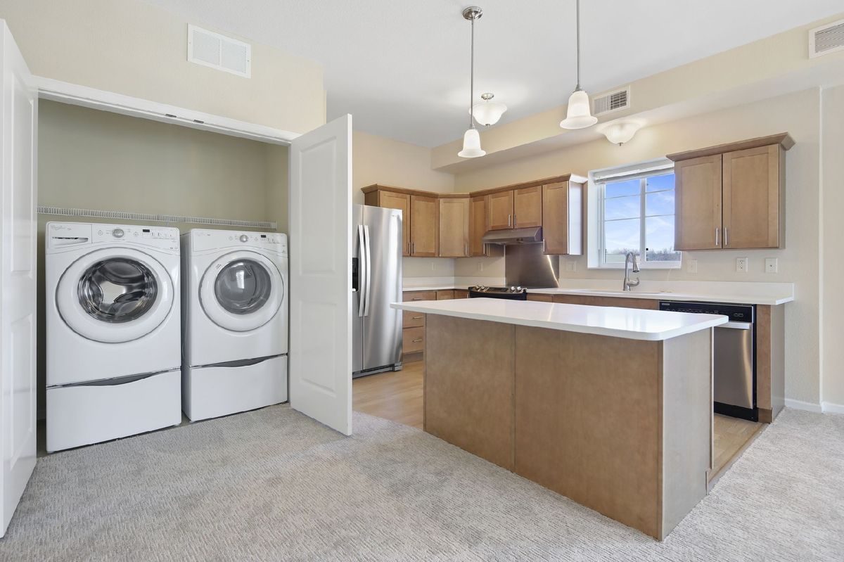 A modern kitchen with an island and adjacent laundry area.
