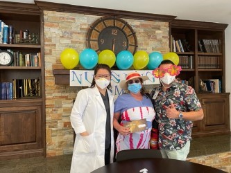 A group of people celebrating with decorations, including balloons and a person in a doctor costume.