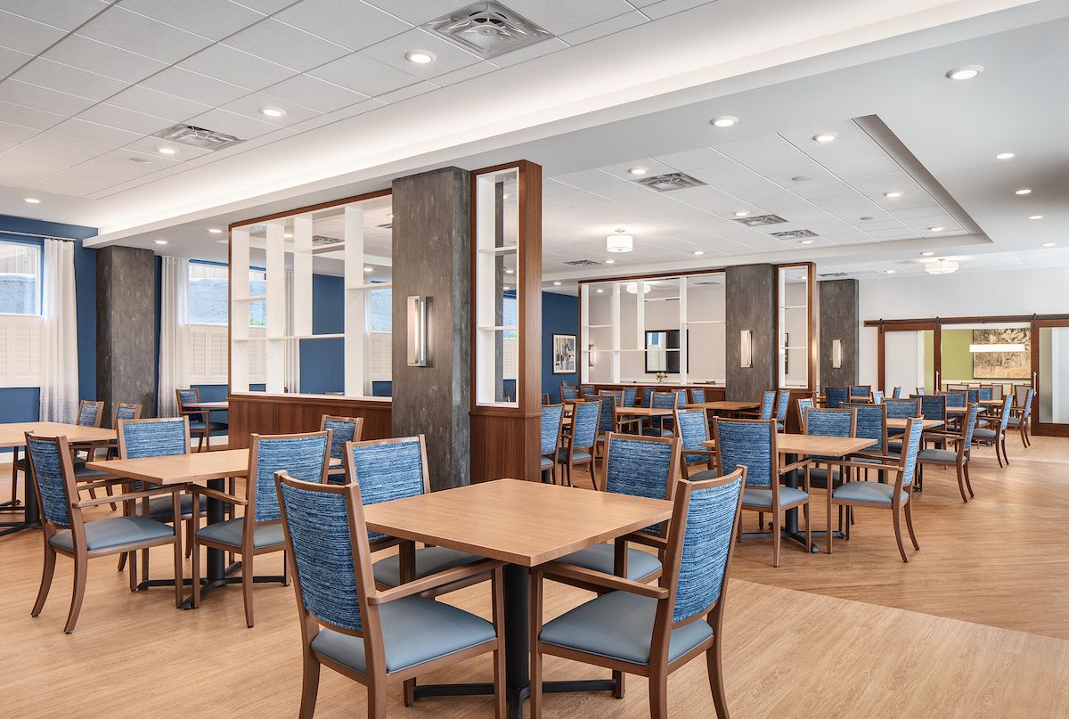 A modern dining area with wooden tables and blue upholstered chairs.