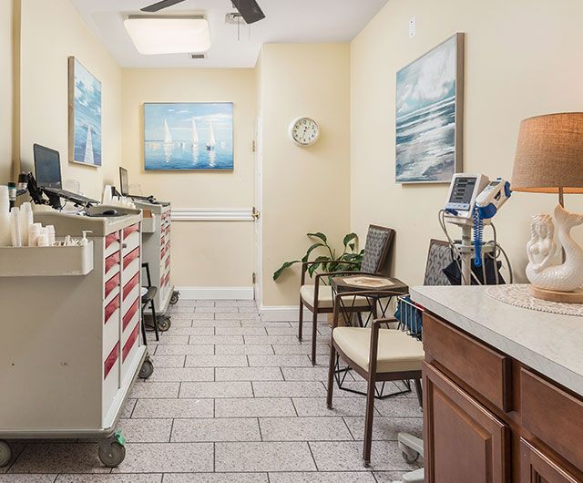 A small medical office waiting area with chairs, medical equipment, and artwork on the walls.
