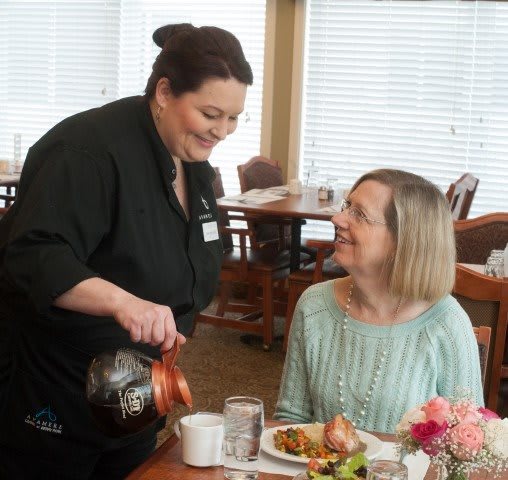 A waitress pours coffee for a customer in a restaurant setting.